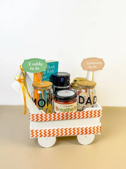 A 'Mommy to be' and 'Daddy to be' gift hamper, cleverly arranged in a decorative cart. This is a great example of creative styling for a baby shower gift.