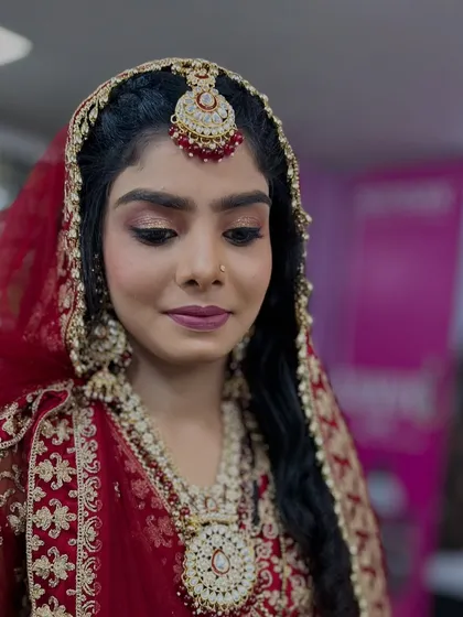 A close-up of the bride's makeup, featuring soft gold and pink eyeshadow, winged liner, and a matte lip.