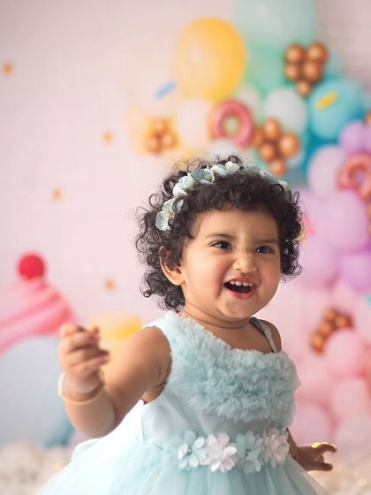 Oh, that sweet, cheeky grin just makes my day. This little doll absolutely rocked her donut-themed cake smash session, and her personality shines through in every shot.