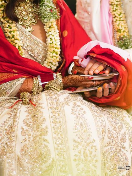A detailed shot of the bride's hands during a wedding ritual, showcasing her intricate henna and the traditional elements of the ceremony.