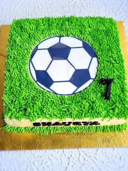A top-down view of the football field cake, showing the edible soccer ball image and the number seven for the birthday boy.