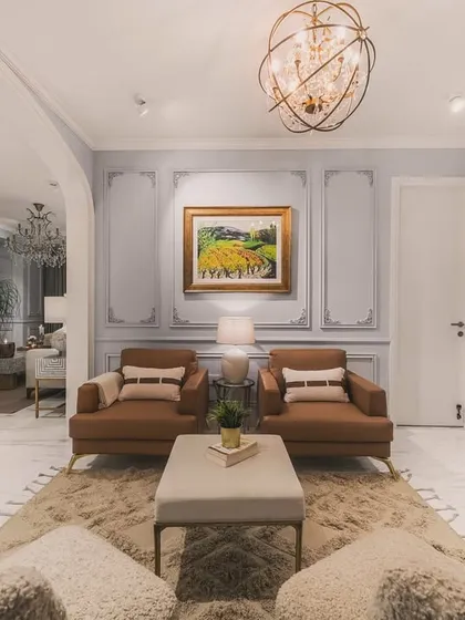 This perspective from behind the textured armchairs offers a deeper view into the open-plan living space. The shot highlights the room's layered design, from the cozy seating area in the foreground to the secondary living space in the back.