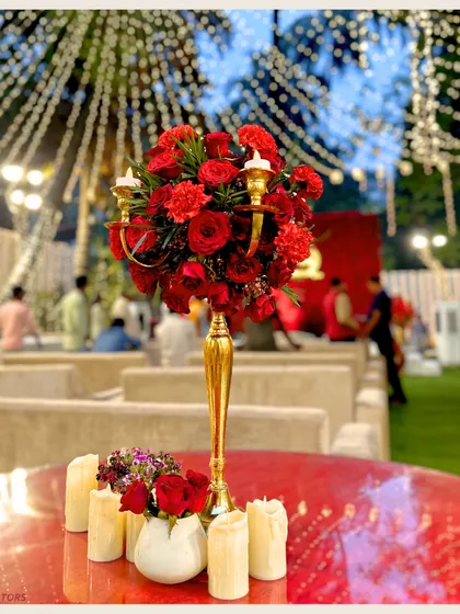 A beautifully set table is key to the guest experience. This centerpiece of red roses and candles on a gold candelabra adds a touch of elegance and romance to the dinner setting.