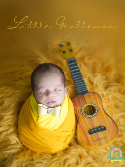 Our "Little Gentleman" setup, featuring a newborn with a tiny bow tie and a miniature guitar. This shows how we can incorporate your hobbies and interests into the shoot.
