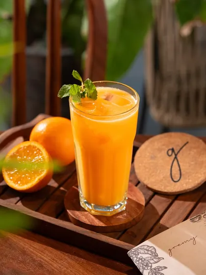 A glass of fresh orange juice on a wooden tray. The simplicity and natural lighting convey freshness and quality.