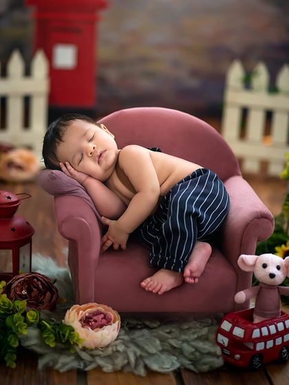 A close-up on the mini sofa, where this little boy is curled up and sleeping so soundly, lost in his dreams.