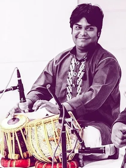 A pleasant portrait of me with my tabla, taken during a concert. I am seated on the stage, looking towards the audience before or after a performance.