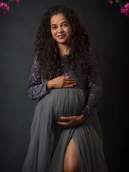 A gentle, classic pose for a maternity portrait. The focus here is on the mother's happy expression and the loving way she holds her baby bump, creating a warm and timeless memory.