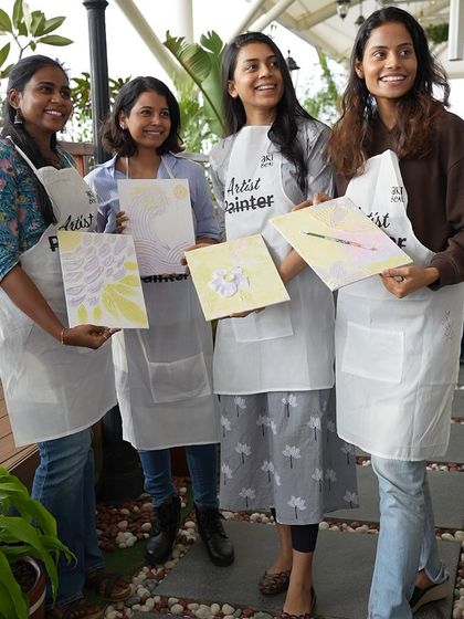 A group of women from a corporate workshop proudly display their finished texture paintings. Art is a fantastic way to foster creativity and teamwork.