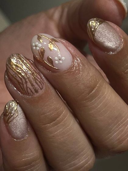 An elegant and intricate design featuring a shimmery nude base with delicate, hand-painted gold floral and leaf patterns.
