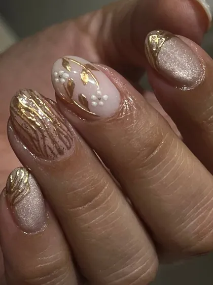An elegant and intricate design featuring a shimmery nude base with delicate, hand-painted gold floral and leaf patterns.