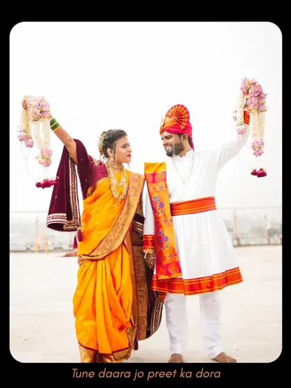 The couple stands together, holding their garlands high in a moment of celebration. This portrait captures their traditional attire and the proud, happy start to their new life.
