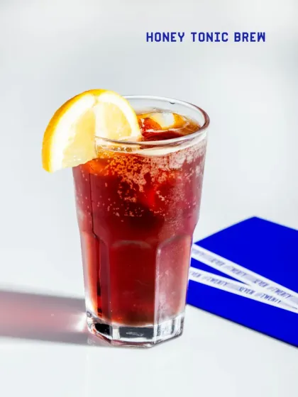 The Honey Tonic Brew is a refreshing mix of cold brew coffee and tonic water, sweetened with a touch of honey and garnished with lemon.