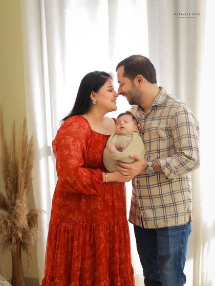 A lovely family portrait where the parents are nose-to-nose, sharing a sweet moment while holding their baby. It’s a perfect picture of a happy, loving family unit.