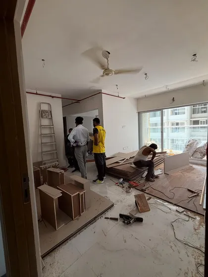 A wide shot of a living room under construction, showing the scale of the woodwork and the team at work.