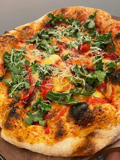 A full view of my artisan pizza with roasted peppers and arugula. The crust is sturdy enough to hold the toppings while remaining incredibly light and airy.