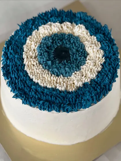 An evil eye theme cake, designed with intricate piping to create the iconic symbol. It's a unique and meaningful design for a special occasion, made to protect and celebrate.