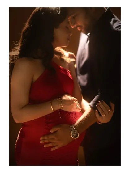 A close-up of intimacy and connection. This studio shot focuses on the couple's embrace, with the warm, dramatic lighting highlighting their hands on the baby bump, telling a story of shared love and anticipation.