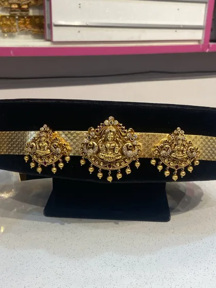 A detailed shot of a traditional vaddanam (waist belt) and vanki (armlet) set, featuring Goddess Lakshmi motifs.