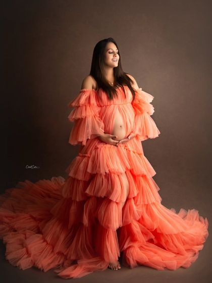Capturing the pure joy of motherhood. This beautiful mom-to-be is glowing in a voluminous, layered orange gown that makes a bold statement.