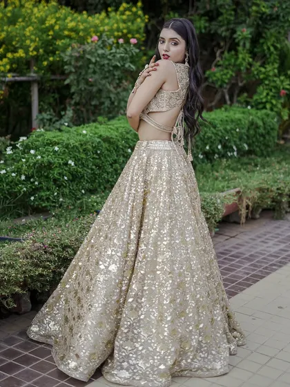 Go for gold with this dazzling sequined lehenga. The backless blouse design adds a modern, glamorous touch, making it an ideal choice for a sangeet or cocktail party.