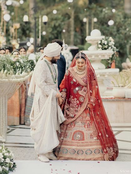 The groom, Kunal, gently guiding his bride, Parul, during the ceremony, a gesture of care and partnership.