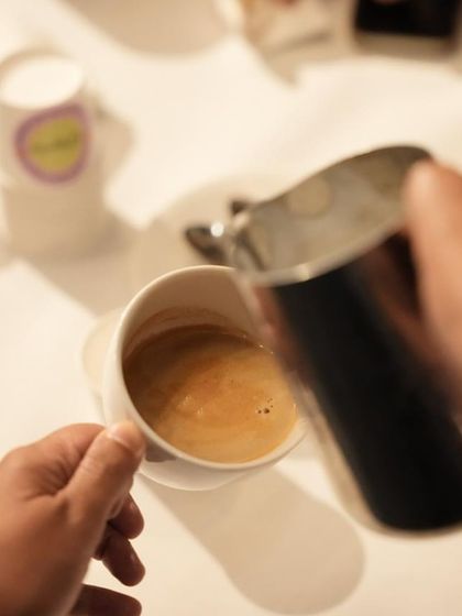 A first-person view of pouring steamed milk into espresso. This is the moment where the art begins to take shape.