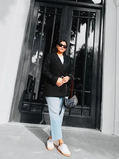 A minimalist and chic look featuring a black oversized blazer, a simple white tee, and light-wash jeans. This full-length shot showcases a classic, effortless street-style outfit.