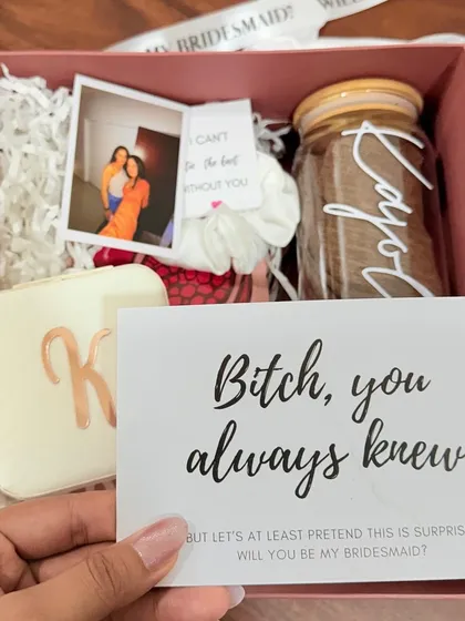 It's all in the details. This close-up shows a custom bridesmaid proposal box, featuring a personalized jewelry case, a photo memory, and a fun, cheeky proposal card that perfectly captures the friendship.