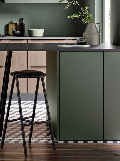 A detail of the island in the metallic green and walnut kitchen. The slim profile of the breakfast bar adds a light, contemporary touch.