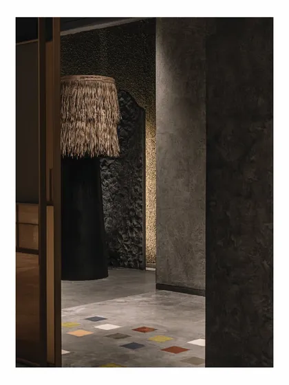 Another view of a Zen garden space in the 'Frozen' store, featuring a large floor lamp with a thatch shade. The interplay of rough textures, dark tones, and carefully placed lighting creates a deeply atmospheric and memorable corner.