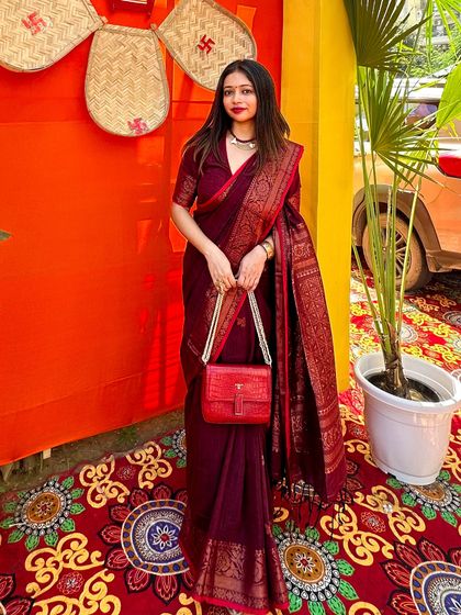 Holding my red bag against the deep maroon saree. This shows how I play with color blocking to create a visually interesting and coordinated festive outfit.