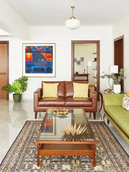 Here, a modern leather sofa is paired with a vintage-style green couch and colorful abstract art. This mix of styles creates a dynamic and inviting living area that feels collected over time, reflecting a unique and personal taste.