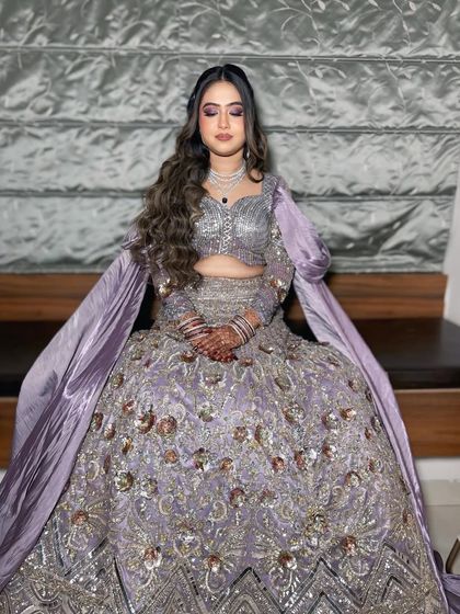 A full look at this gorgeous lavender outfit. The makeup and hair are designed to complement the intricate details of the lehenga, creating a princess-like feel.