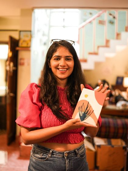 A participant smiles as she holds her beautiful abstract painting from the workshop.