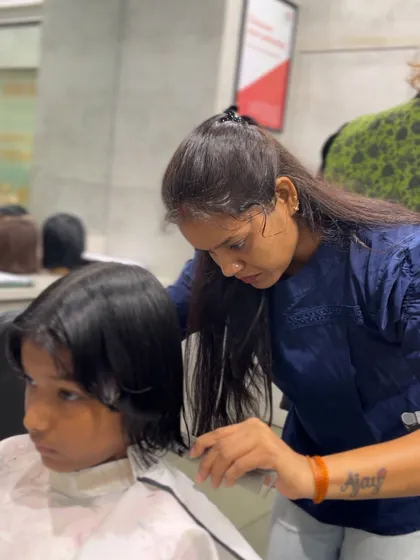 A student focuses on the details of a haircut, learning the precision required to become a professional hairstylist.