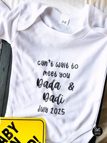 A close-up of the custom 'Can't wait to meet you Dada & Dadi' onesie. The simple, clean design makes the message stand out.