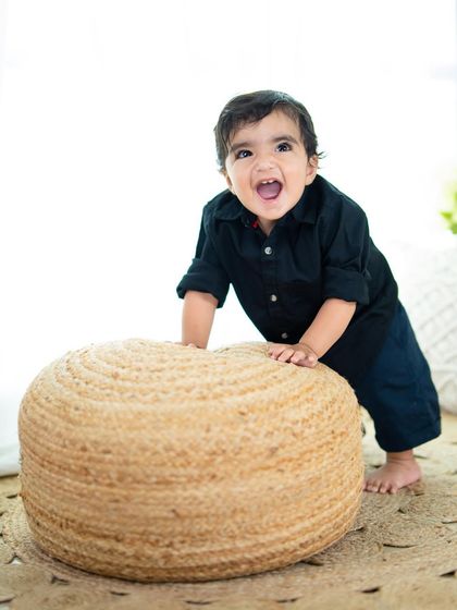 A burst of happy energy from this little boy as he plays on a jute pouf in the studio.