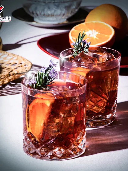 Two glasses of a rich, dark cocktail garnished with orange and rosemary. This image evokes a sense of warmth and relaxation, perfect for unwinding.