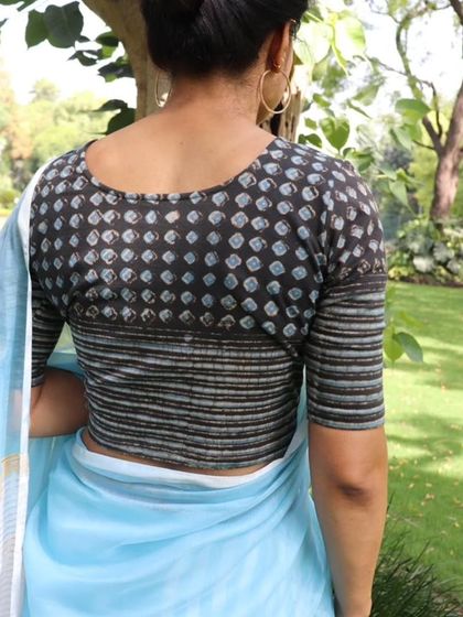 The back view of a stylishly tailored blouse, combining a dotted Ajrakh or Dabu print with a striped fabric.