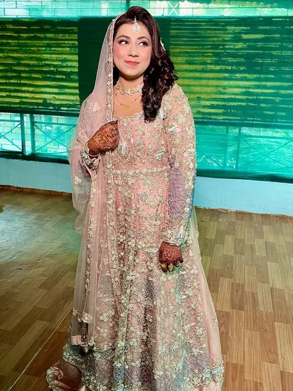 A full-length shot showcasing the beautiful pastel gown. The soft makeup look complements the delicate embroidery without being overpowering.