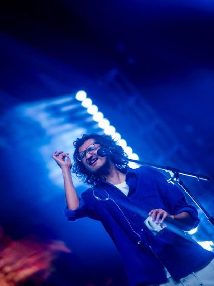 An artist performing under a wash of cool blue light. I design sophisticated lighting schemes that set the mood and create a visually stunning atmosphere for live music events.