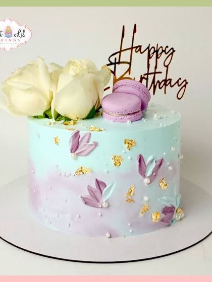 A dreamy pastel birthday cake with fresh white roses, lavender macarons, and flecks of gold leaf for a touch of luxury.