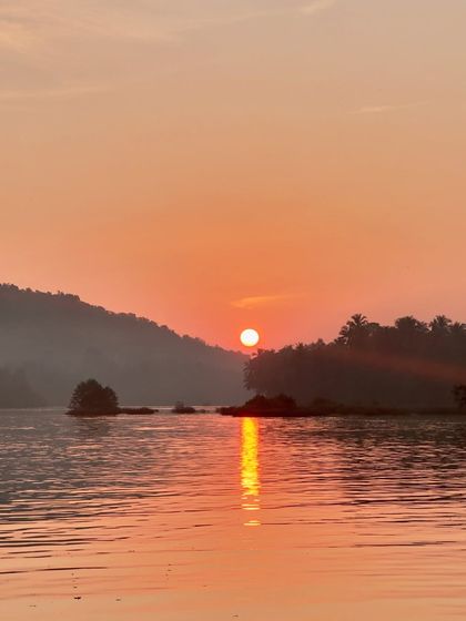 The sun setting over the hills, its reflection shimmering on the water, a beautiful view from our boat.