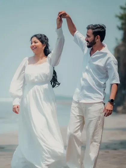 A joyful, spontaneous dance on the beach. This photo captures a moment of pure happiness and movement, with the bride's white dress flowing in the gentle sea breeze.