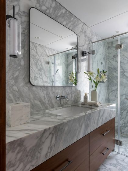 Another bathroom from the Parishram project, showcasing a beautiful grey marble. The custom wooden vanity adds warmth to the space, while the mirrored cabinet provides discreet storage.