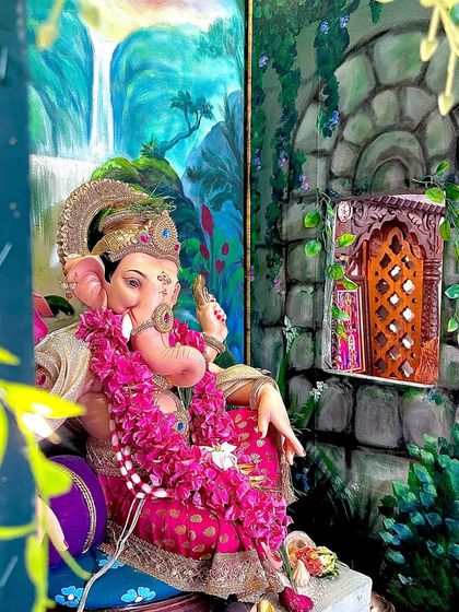 A close-up view of the details. The hand-painted stone window on the side wall and the lush greenery in the backdrop are designed to create a complete, three-dimensional scene for the Ganpati murti.