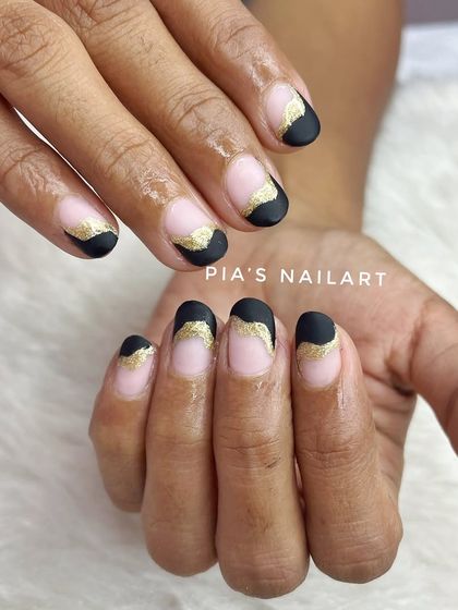 A chic design on natural nails, featuring a matte black tip with a gold glitter accent.