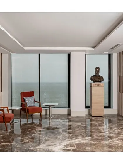 The visitor waiting lounge is designed without a traditional reception desk, instead using comfortable seating and a bust sculpture to create an elegant space with panoramic sea views.