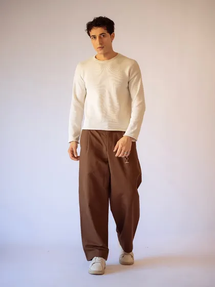 A full-length view of the minimalist look. The natural grooming complements the neutral color palette of the clothing.